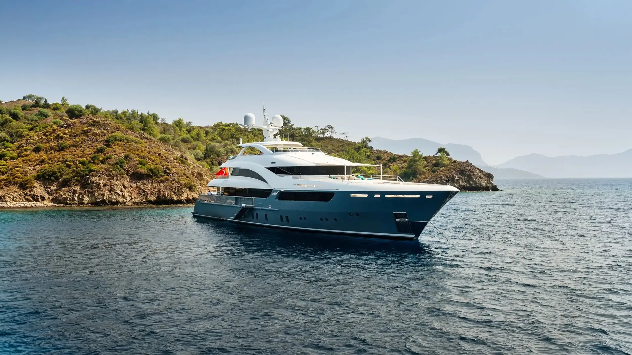 Superyacht anchored near a rocky coastline